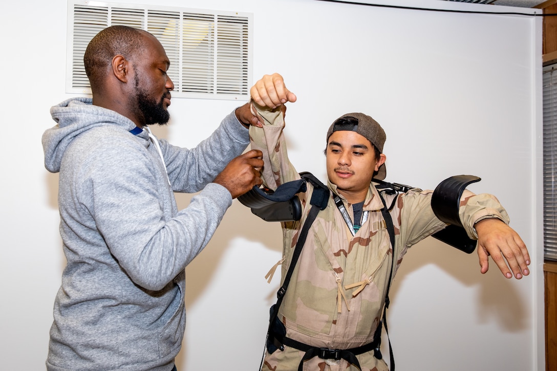 Ergonomics Program Manager James Musgrove fits a Code 900F employee with the Levitate Airframe exoskeleton suit.