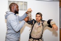 Ergonomics Program Manager James Musgrove fits a Code 900F employee with the Levitate Airframe exoskeleton suit.