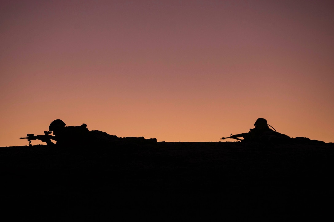 A silhouette of two Marines on the ground pointing their weapons.