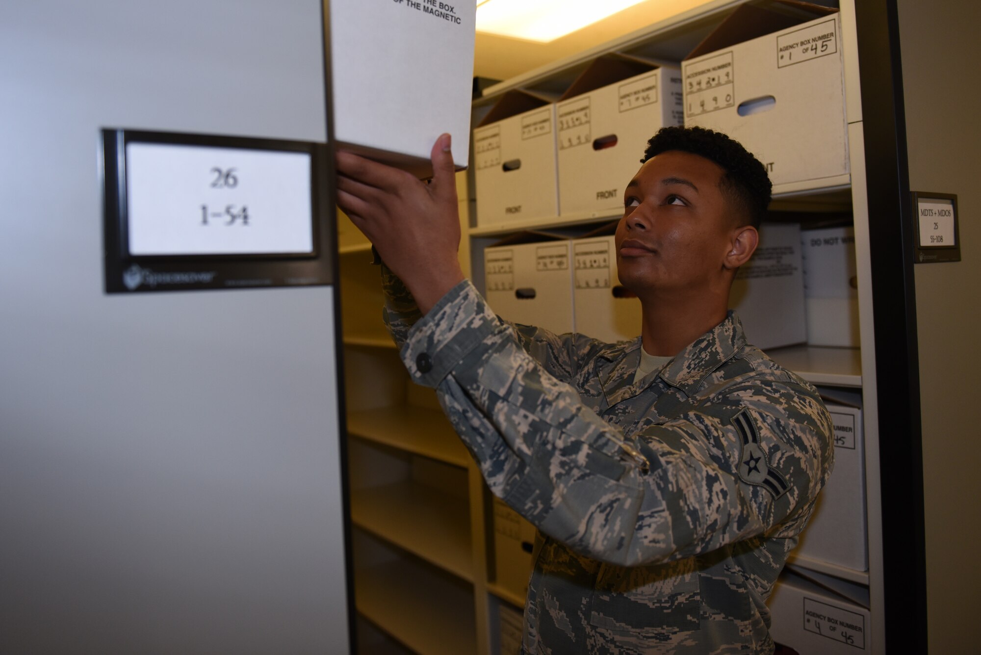 U.S. Air Force Airman 1st Class William Stokes, center, 60th Communications Squadron knowledge management technician, pulls out a box of records of a shelf Nov. 12, 2019, at Travis Air Force Base, California. Stokes was recognized as the Warrior of the Week for Nov. 10-16. The program highlights a Travis Airman for his or her outstanding performance. (U.S. Air Force photo by Airman 1st Class Cameron Otte)