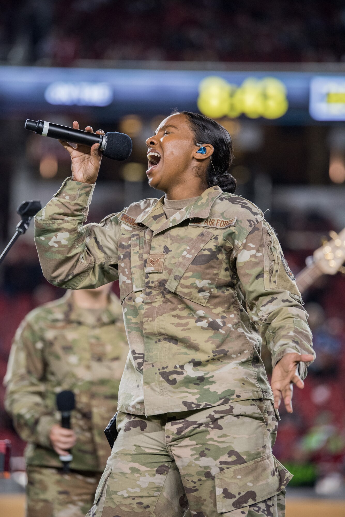 U.S. Airman sings into a microphone during an NFL halftime show