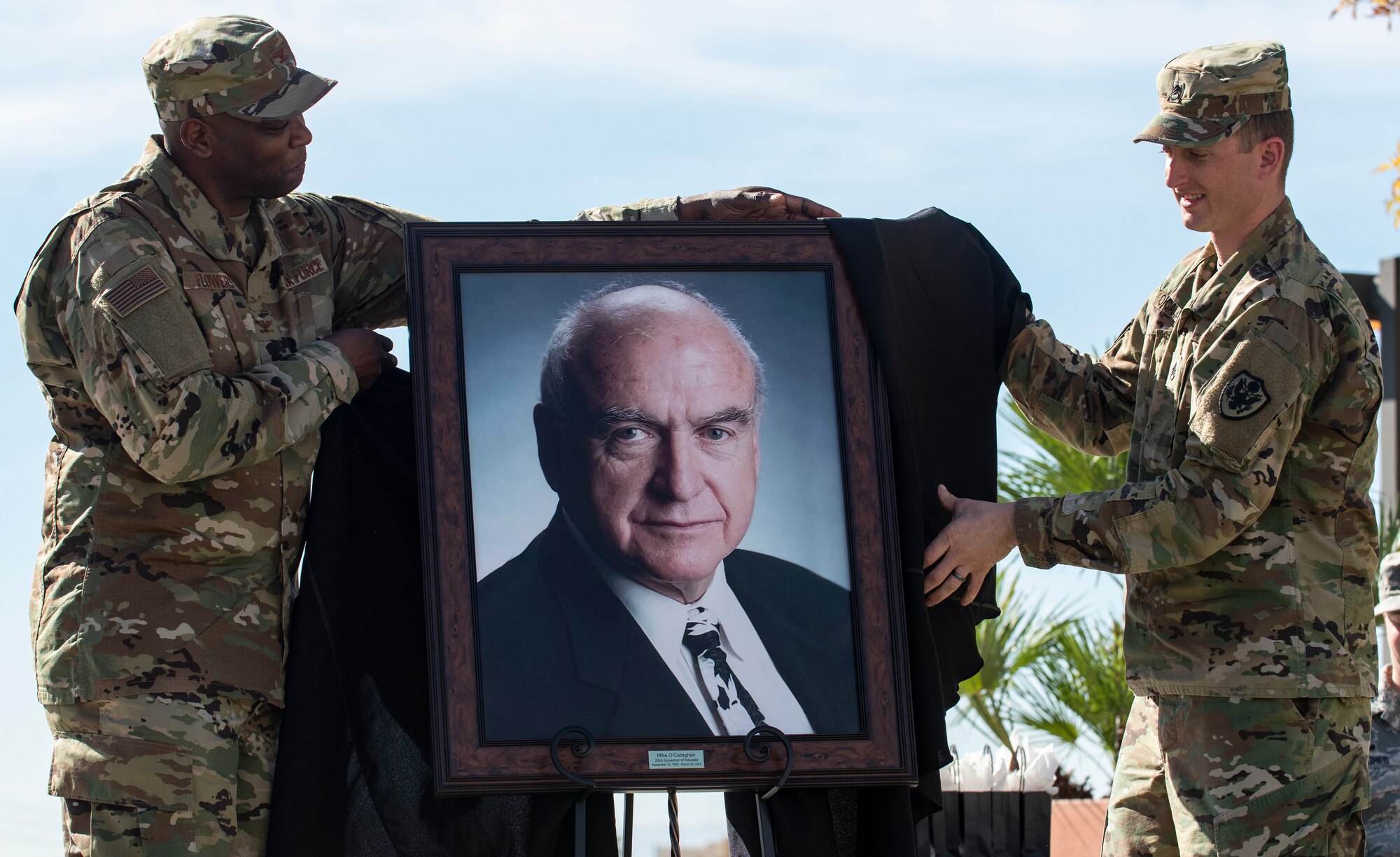 Col. Alfred Flowers, 99th Medical Group commander, and U.S. Army Staff Sgt. Brian O’Callaghan reveal a portrait of O’Callaghan during a ceremony celebrating the Mike O’Callaghan Military Medical Center’s 25th Anniversary on Nellis Air Force Base, Nevada, Nov. 12, 2019. The portrait will hang in the MOMMC to honor the centers namesake. (U.S. Air Force photo by Senior Airman Kevin Tanenbaum)