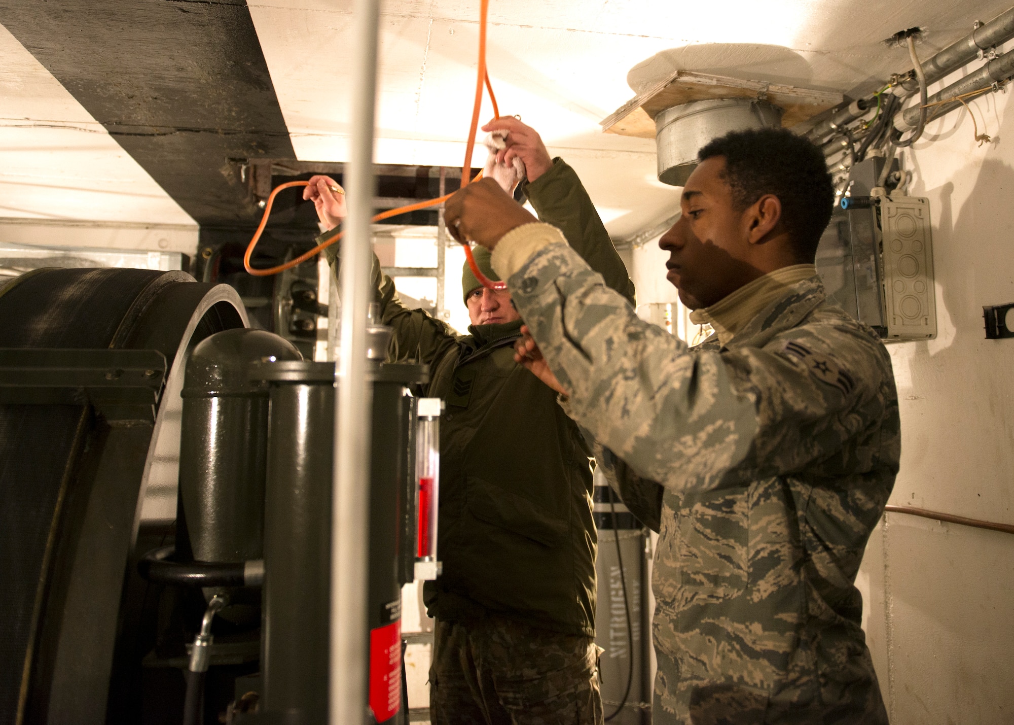 U.S. Air Force Airman 1st Class Marquis Brown, 786th Civil Engineer Squadron power production technician, works with Lithuania air force Pvt. 3rd Class Aurimas Kantauskas, aircraft arresting system technician, on an aircraft arresting system engine at Ramstein Air Base, Germany, Nov. 7, 2019. The aircraft arresting system is a mechanism designed to stop airplanes in the event pilots cannot stop them on their own.