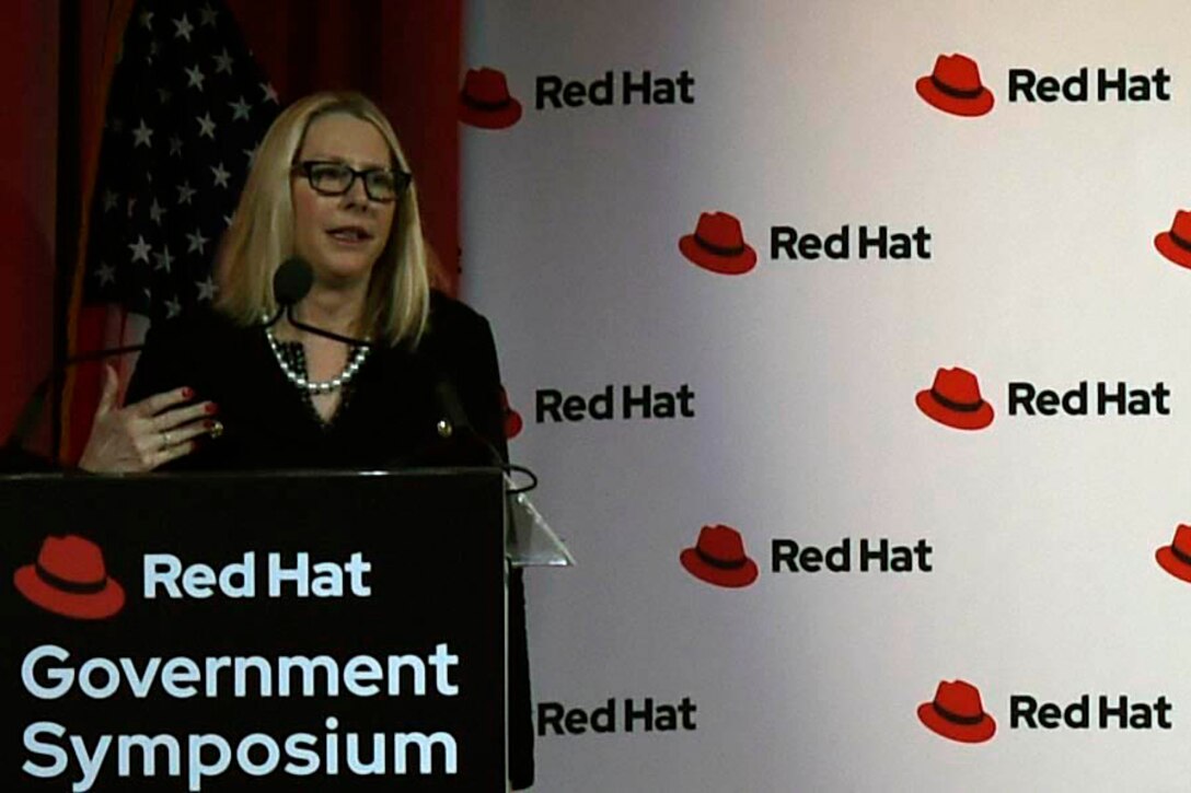 Woman stands behind a podium and speaks into a microphone.