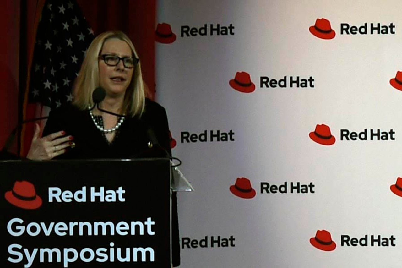 Woman stands behind a podium and speaks into a microphone.
