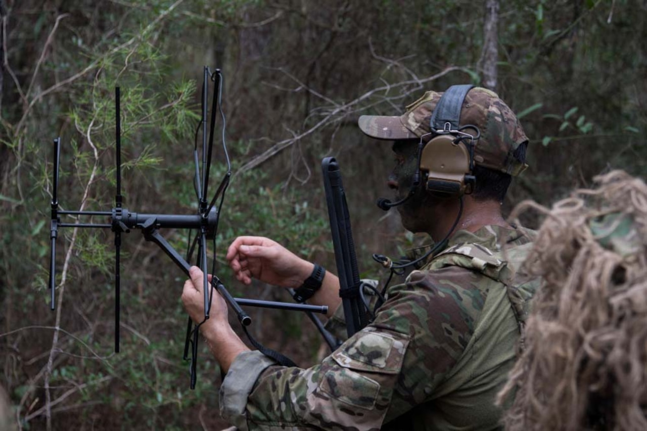 An airman sets up a satellite communications contraption.