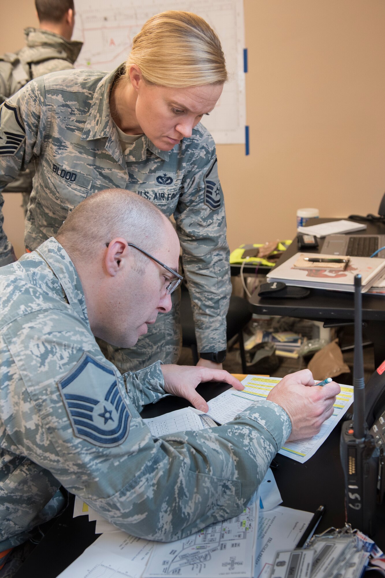 Master Sgt. Jennifer Blood, 167th Airlift Wing emergency managment, and Master Sgt. Anthony Perkins, 167th AW inspections superintendent, look over the schedule of events list for a full-scale readiness exercise, Nov. 4 2019. Approximately 300 members of the 167th Airlift Wing deployed to the Combat Readiness Training Center in Alpena, Mich., Nov. 3-7, for the event.(U.S. Air National Guard photo by Senior Master Sgt. Emily Beightol-Deyerle)