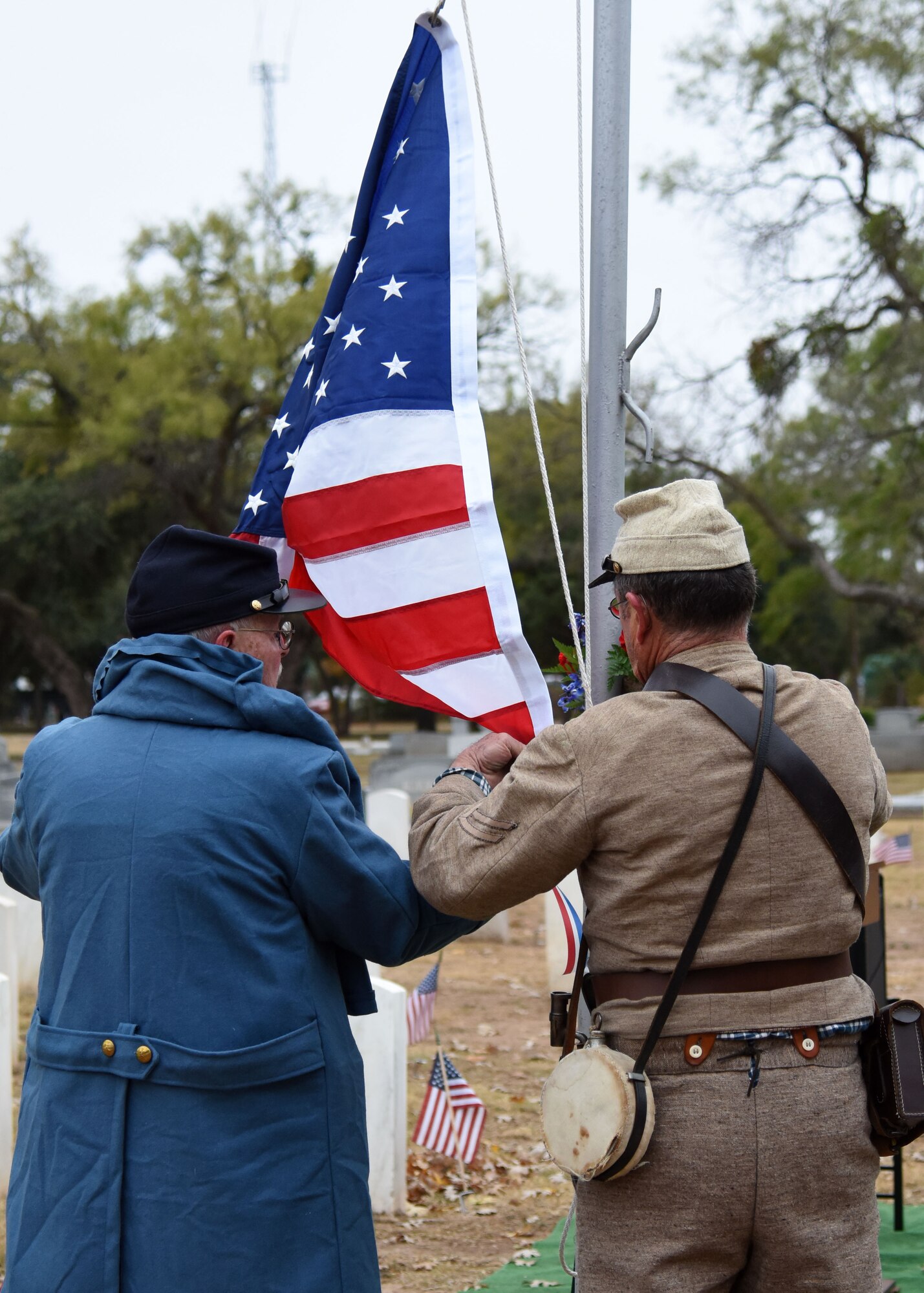 Members of the Tom Green County Historical Commission raise the flag in honor of Veterans Day at the Fairmount Cemetery in San Angelo, Texas, Nov. 11, 2019. The Friends of Fairmount organization invited the city to honor those who have served. (U.S. Air Force Photo by Airman 1st Class Ethan Sherwood/Released)