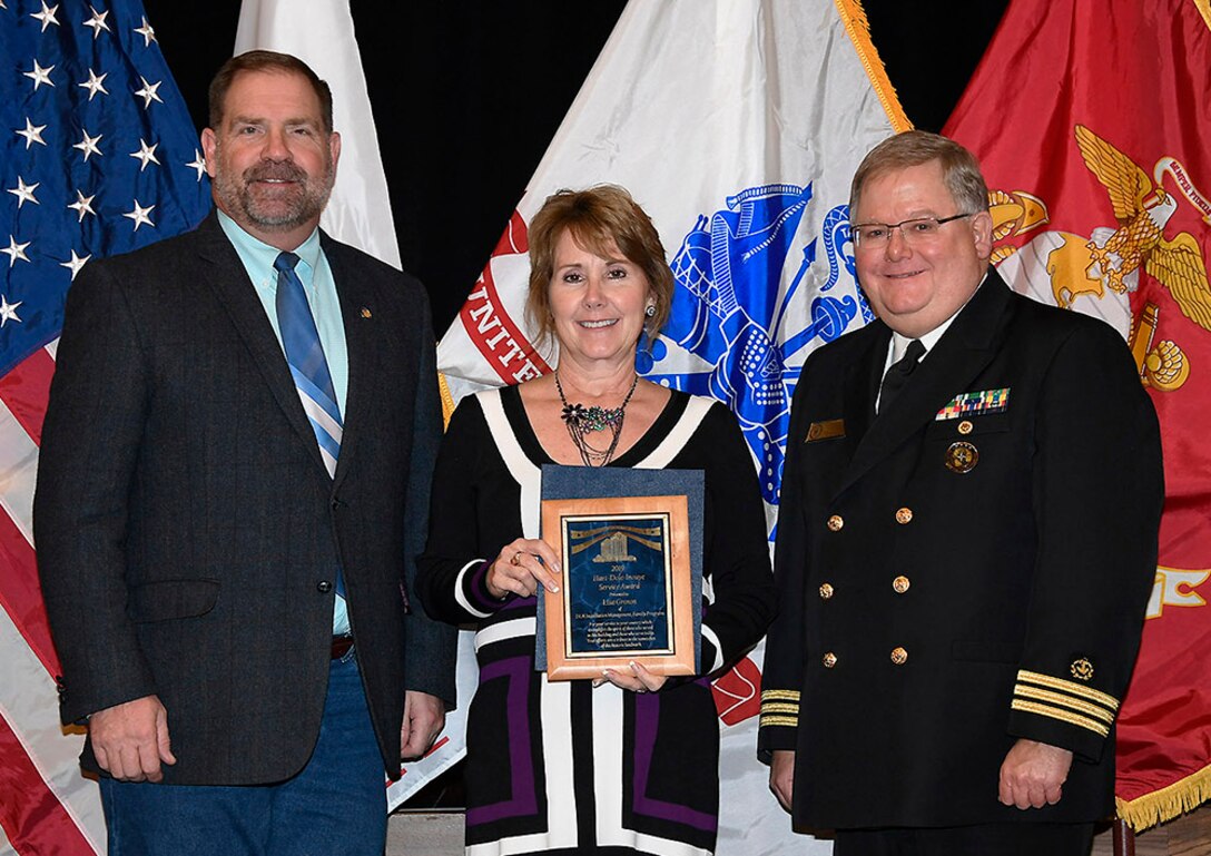 DLA Installation Management’s Lisa Grenon (center) is awarded a 2019 Hart-Dole-Inouye Federal Center Service Award Nov. 8. Also pictured are DLA Disposition Services Director Mike Cannon and Battle Creek Military Affairs Committee Chairman T.R. Shaw, U.S. Navy, retired.