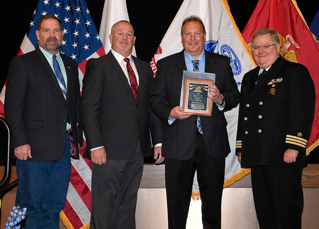 DLA Logistics Information Services’ Thomas Kik (center) is awarded a 2019 Hart-Dole-Inouye Federal Center Service Award Nov. 8. Also pictured are DLA Disposition Services Director Mike Cannon, Logistics Information Services Training Branch Chief Mike Chapman and Battle Creek Military Affairs Committee Chairman T.R. Shaw, U.S. Navy, retired.