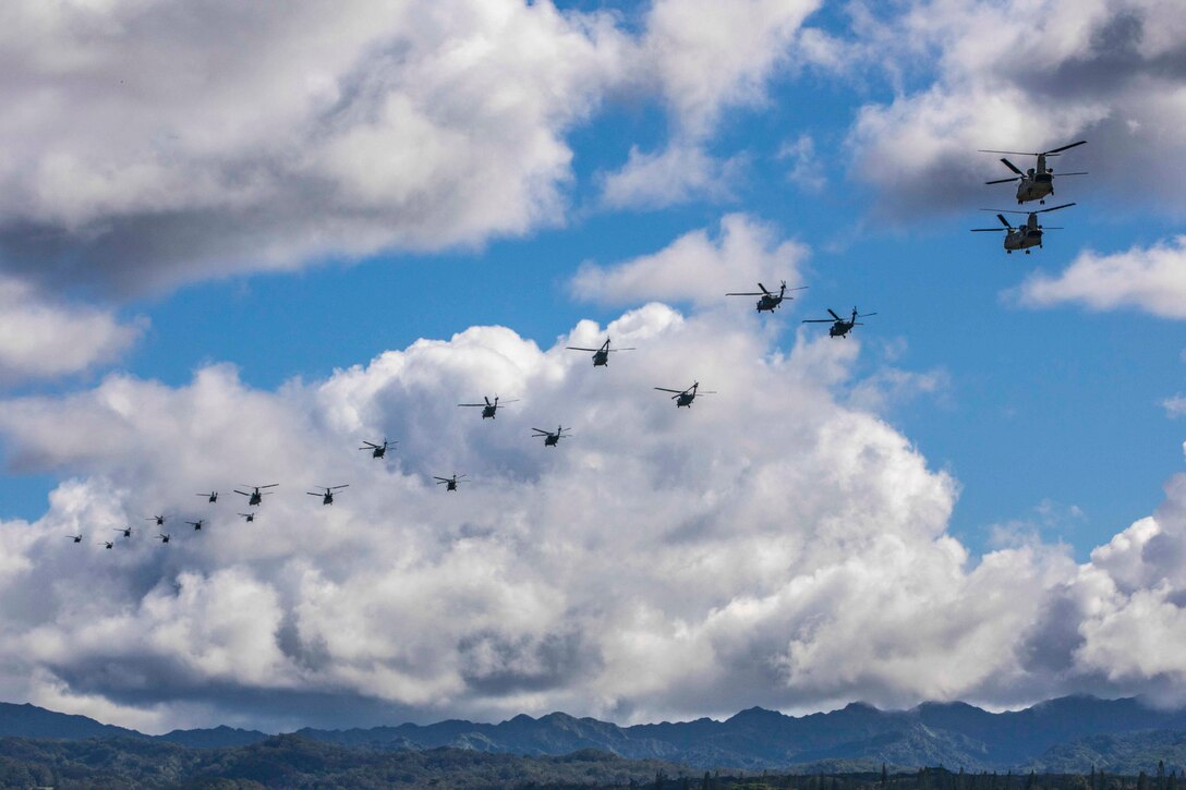 A large group of helicopters travel through the sky.