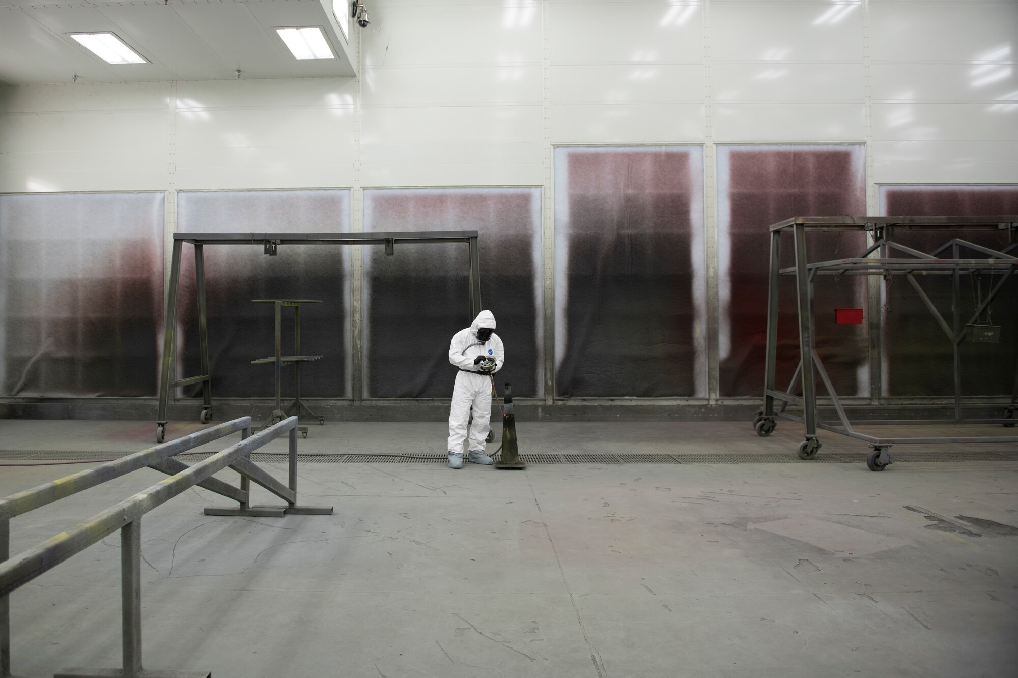 A photo of an Airman preparing an aircraft part to be painted