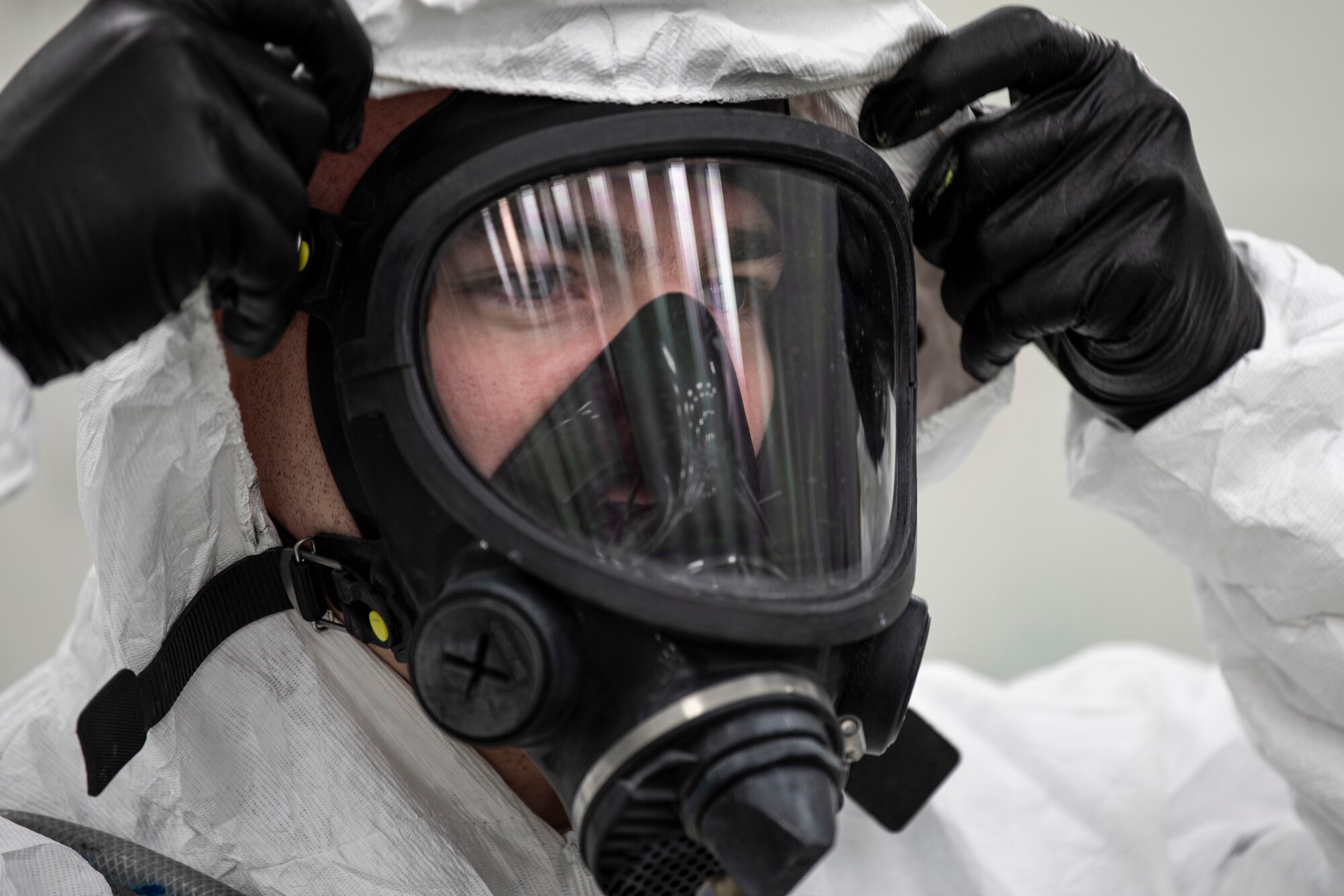 A photo of an Airman donning protective gear before painting an aircraft part