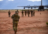 A photo of airmen walking on a dirt runway.