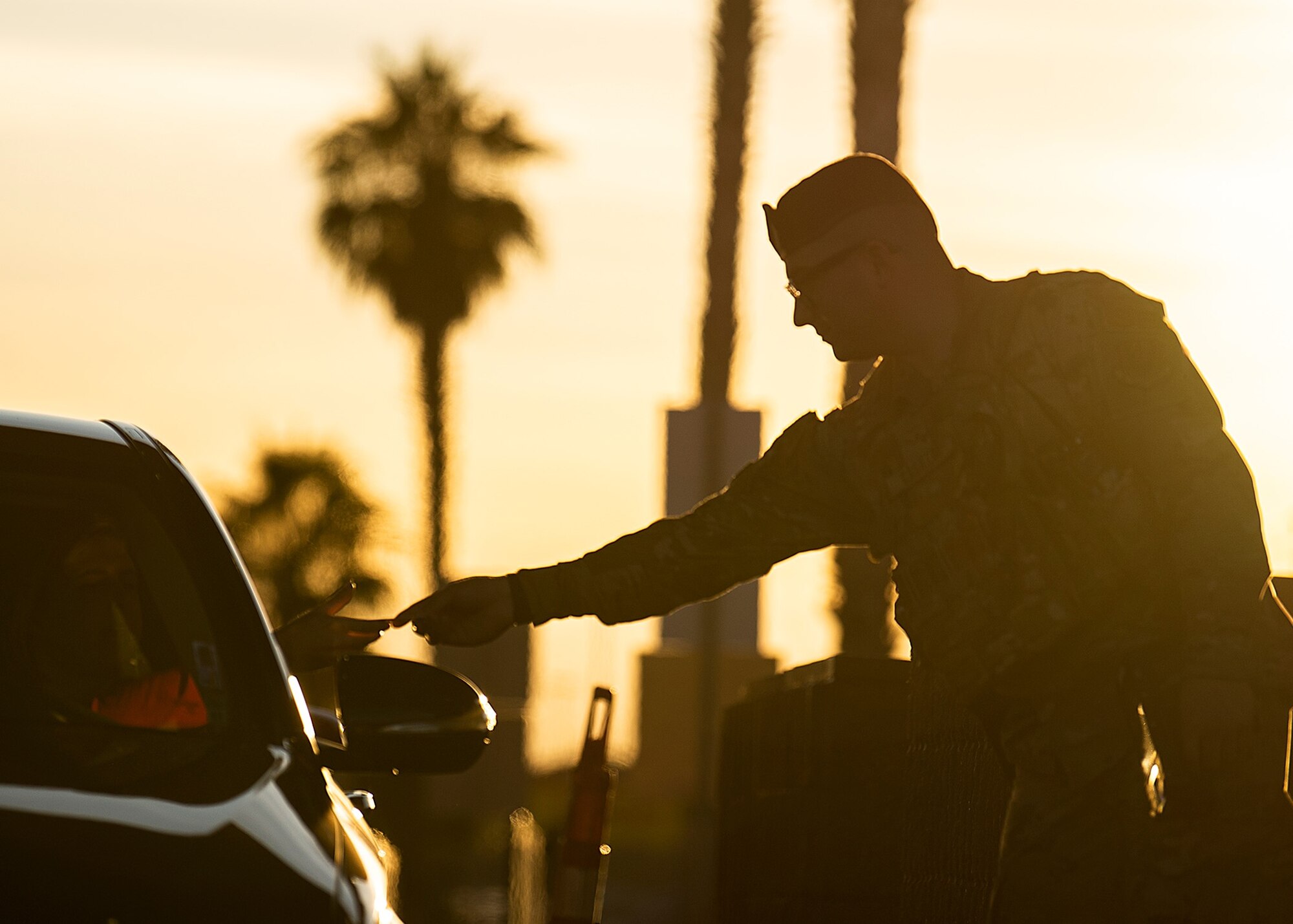 A Security Force member hands an individual in a vehicle their Common Access Card.