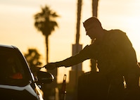 A Security Force member hands an individual in a vehicle their Common Access Card.