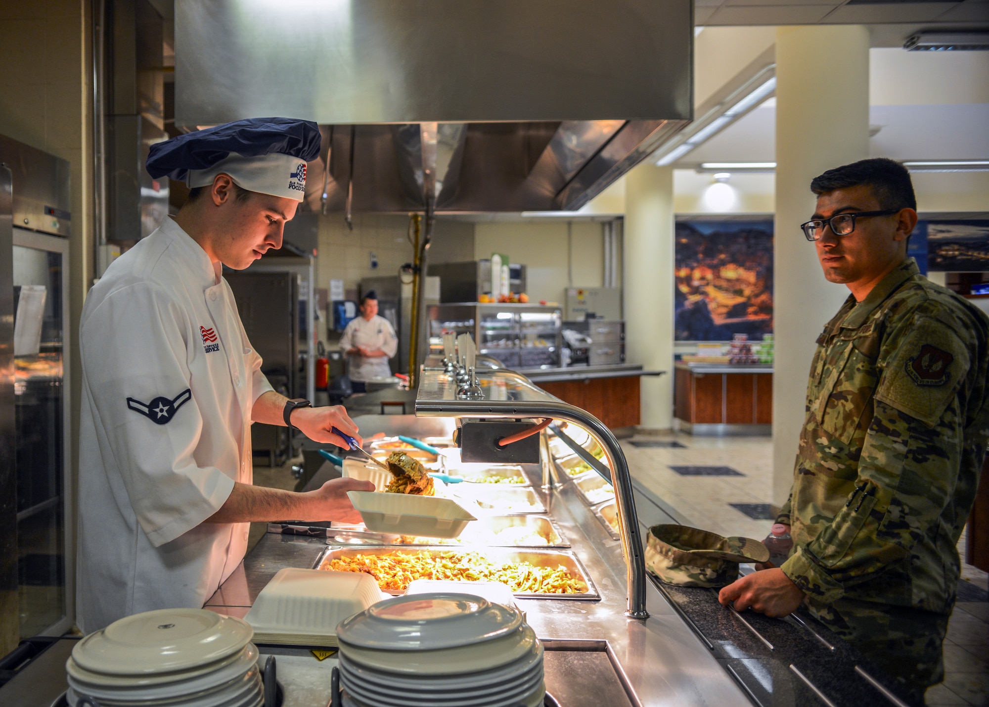 U.S. Airman Kellan S. Hill, 31st Force Support Squadron server, serves an Airman at La Dolce Vita dining facility, Aviano Air Base, Italy, Nov. 7, 2019. Hill joined the military May 7, 2019 and has worked at La Dolce Vita for one month. (U.S. Air Force photo by Airman Thomas S. Keisler IV)