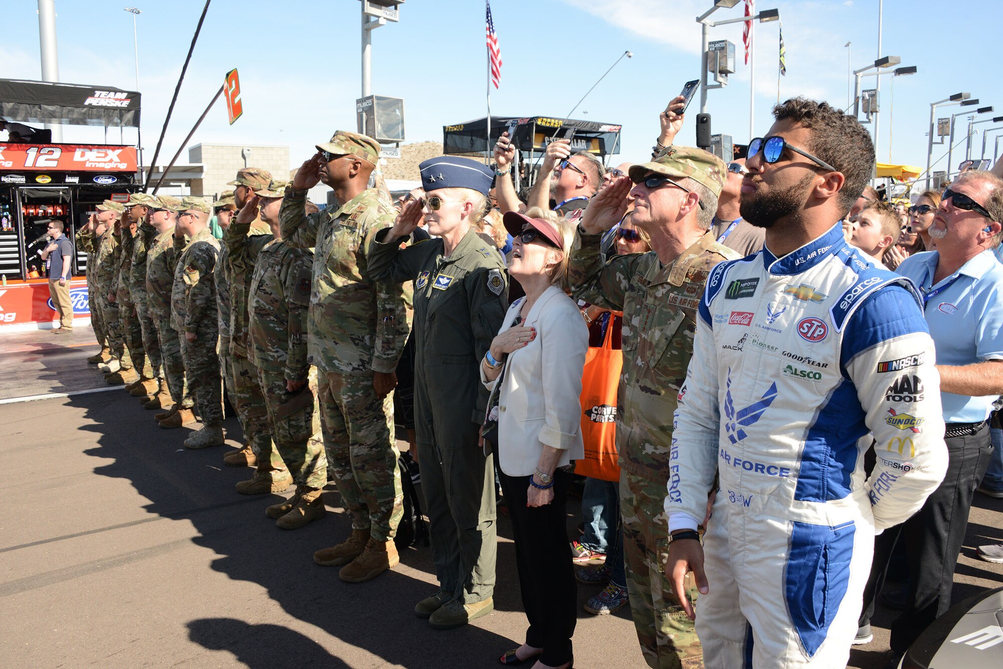 Bubba Wallace, driver of the Air Force No. 43 car, Gen. David. L. Goldfein, the Air Force chief of staff,  and his wife Dawn Goldfien, Maj. Gen. Jeannie Leavitt, Air Force Recruiting Service, commander, and members of the Air Force during the national anthem before the the Bluegreen Vacations 500 NASCAR race in Phoenix.