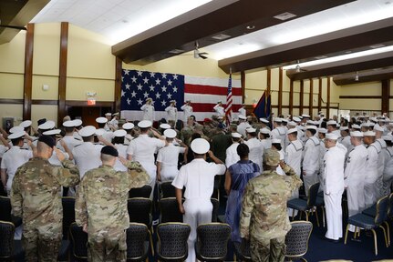 Personnel salute as the color guard parades the colors during a change of command ceremony for HSC-25.