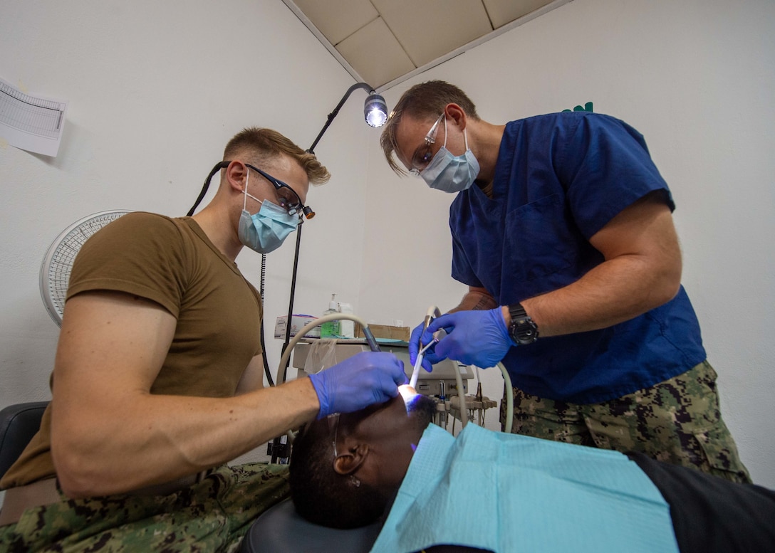 U.S. Navy Lt. Jack Davies, a dentist, and Hospital Corpsman 3rd Class Anthony Serpico, assigned to the hospital ship USNS Comfort (T-AH 20), clean a man’s teeth at a temporary medical treatment site in Port-au-Prince, Haiti, Nov. 9, 2019.