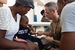 U.S. Navy Capt. Michael Sullivan, a pediatrician assigned to the hospital ship USNS Comfort (T-AH 20), gives a sticker to a two-year-old boy after examining his skin infection at a temporary medical treatment site in Port-Au-Prince, Haiti Nov. 6, 2019.