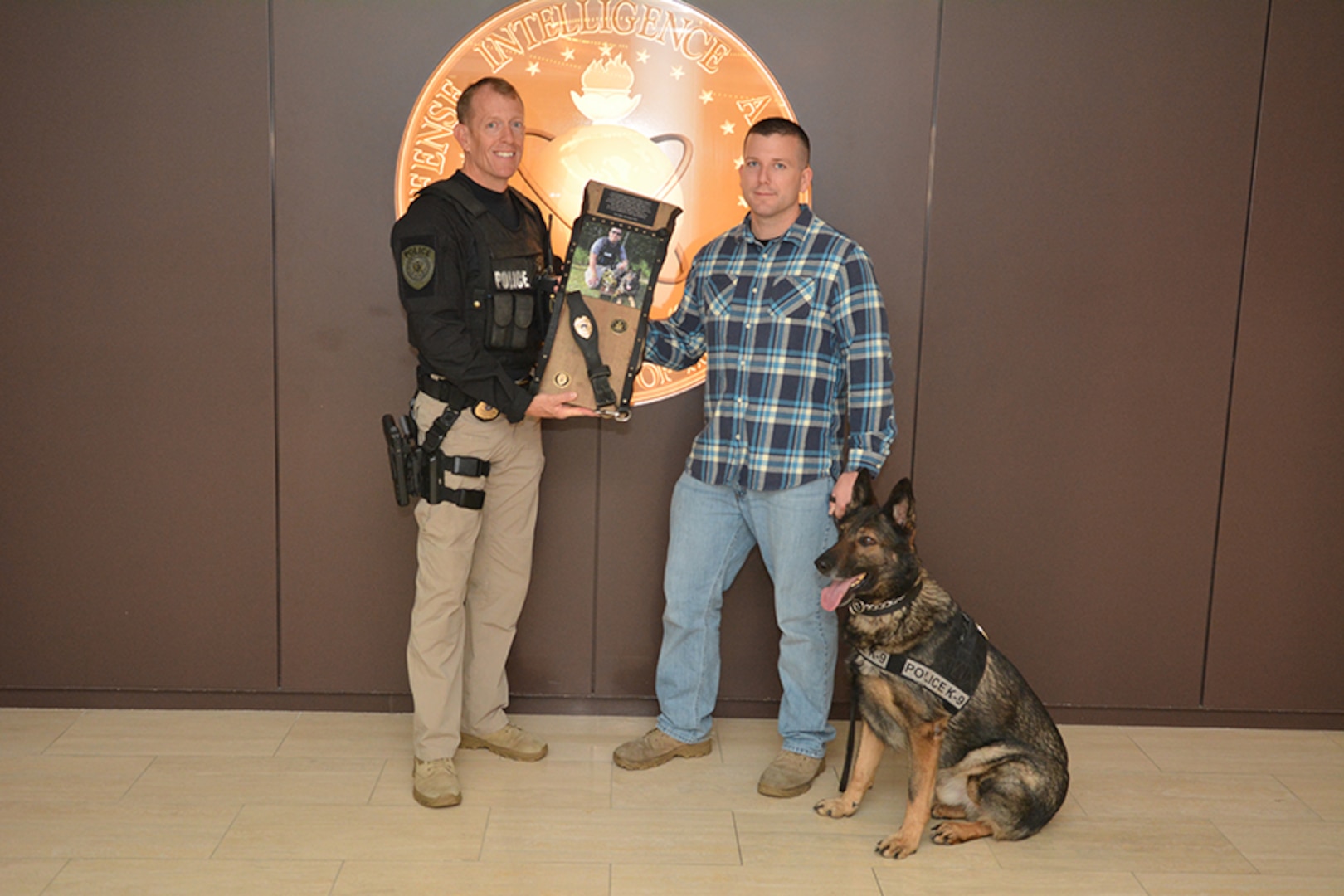Capt. Bill McEnaney, Defense Intelligence Agency Police, presents a commemorative plaque to Scott Frazer for his years of service to the Agency.