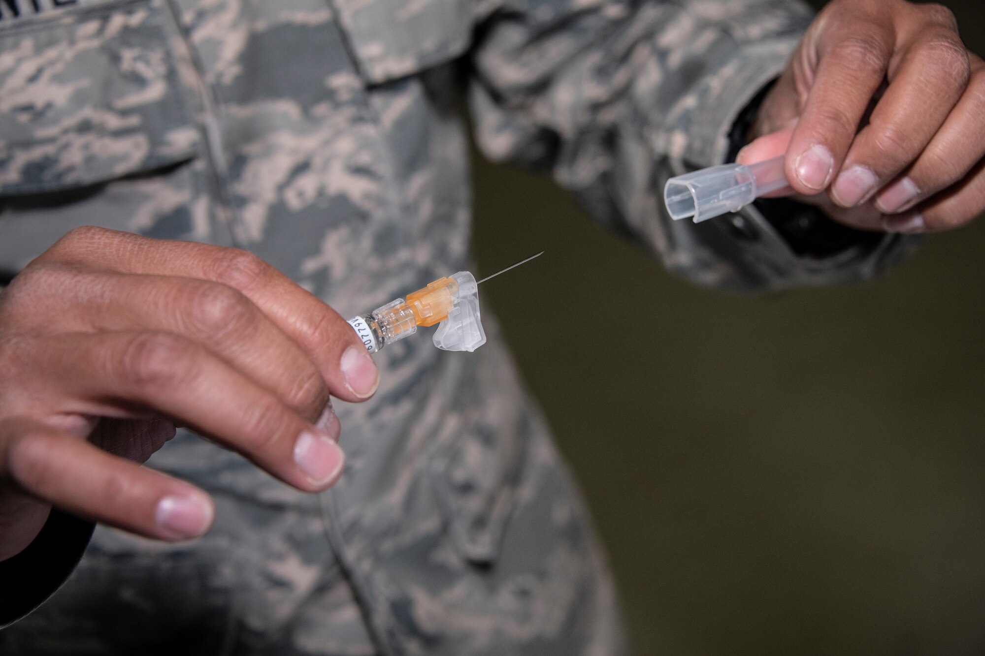 U.S. Air Force Staff Sgt. Harris Belmonte, 60th Aeromedical Squadron medical technician, prepares an influenza vaccine during a mass inoculation at the “Point of Distribution” during a base exercise Nov. 5, 2019, at Travis Air Force Base, California. The exercise tested Team Travis’ ability to respond to a public health emergency in the event of an actual health crisis. (U.S. Air Force photo by Heide Couch)