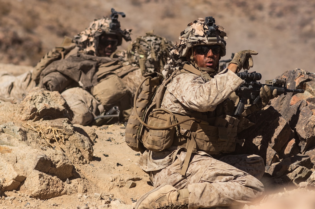 A group of marines do hand signals from the ground.