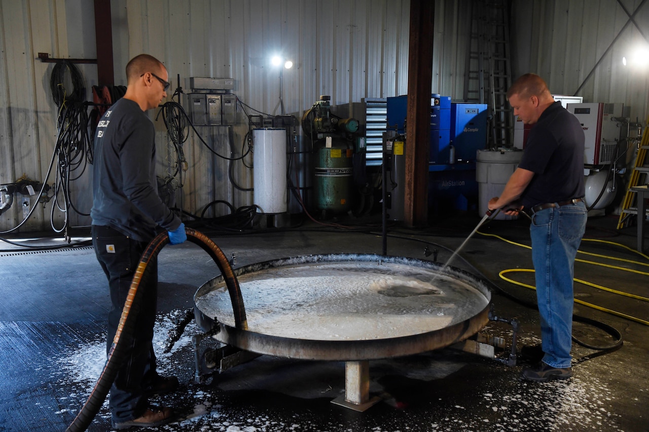 Researchers use hoses to clean firefighting foam out of container.