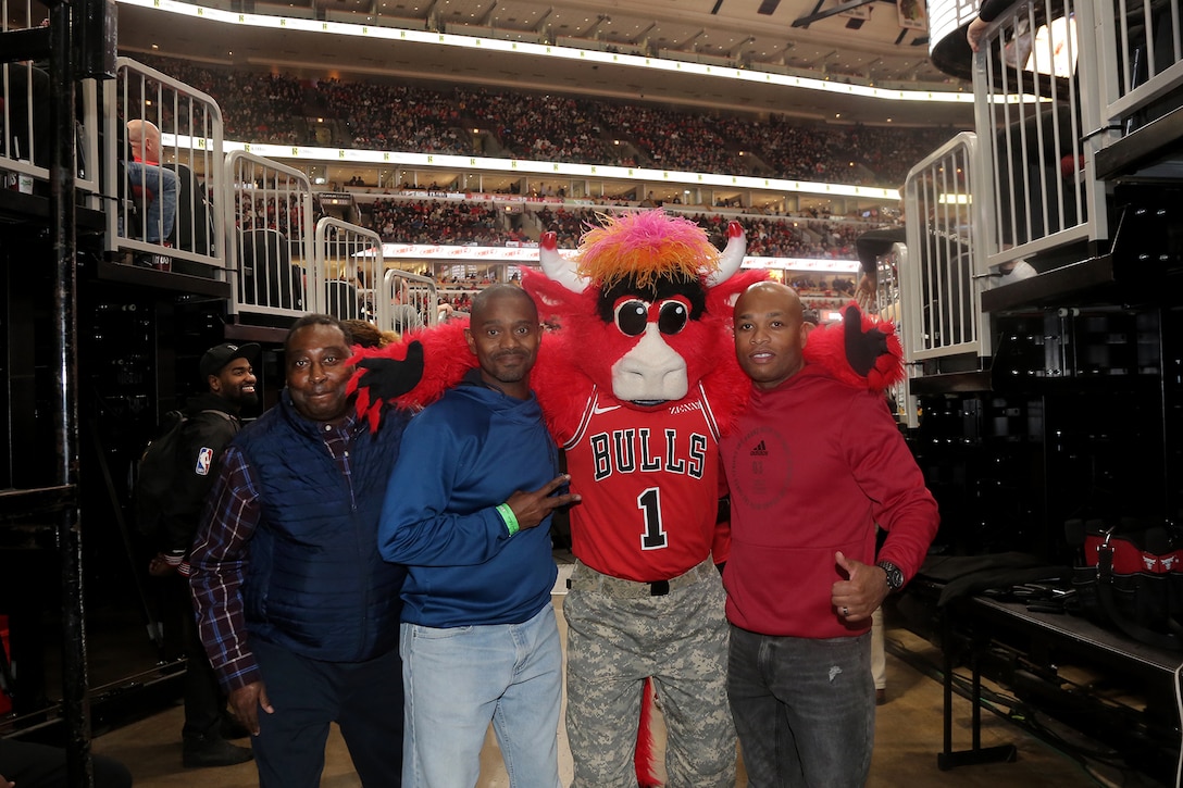 (From left to right) Chief Warrant Officer 3 William Brinston, Chief Warrant Officer 4 Tilmon Wooden, and Master Sgt. Laroy Warren pause for a photo with Benny the Bull, Chicago Bulls mascot, at a military appreciation game at the United Center in Chicago, November 9, 2019.