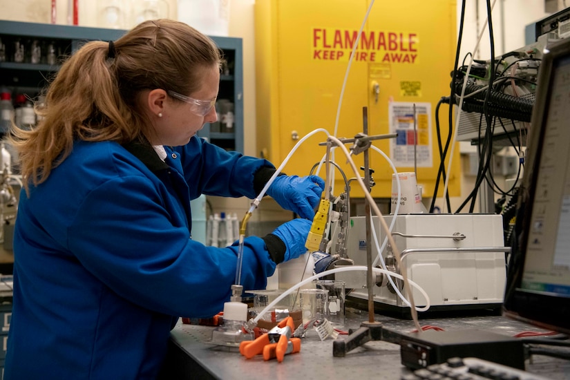 A chemist in a lab begins filling a plastic container with foam.