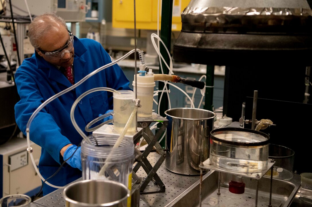 A chemist in a lab begins filling a metal container with foam.