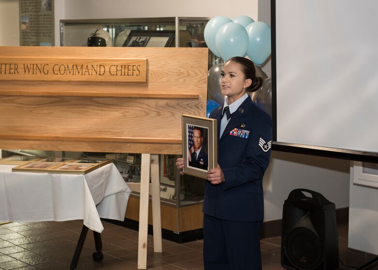 Staff Sgt. Alexandra Christofferson, 366th Force Support Squadron NCO in charge of outbound assignments, reads a biography for retired Chief Master Sgt. John Weimer, former 366th FW command chief at a ceremony, Nov. 11, 2019, at Mountain Home Air Force Base, Idaho. The ceremony entails honoring MHAFB’s top enlisted leaders who’ve served in the 366th FW as senior enlisted advisors. (U.S. Air Force photo by Senior Airman Tyrell Hall)