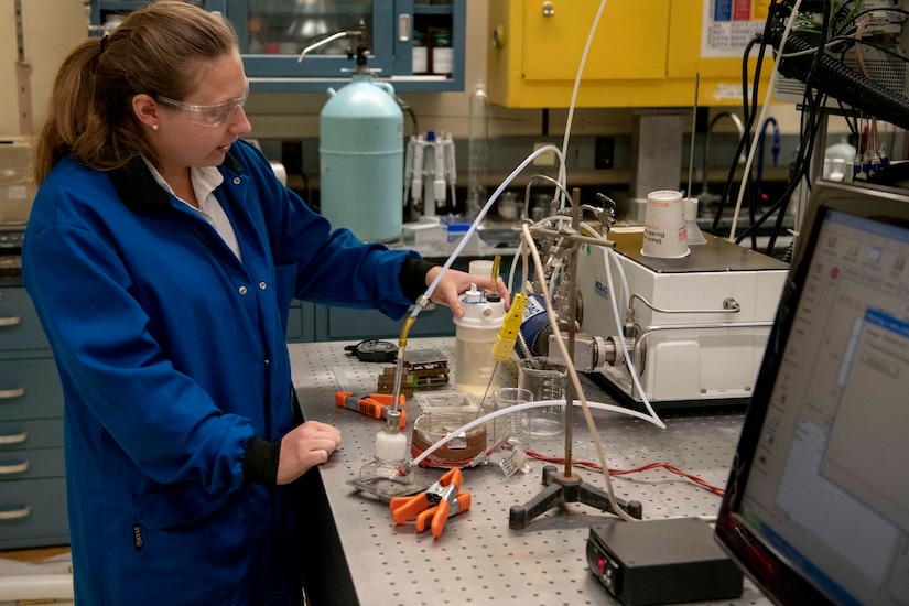 A chemist in a lab begins filling a plastic container with foam.