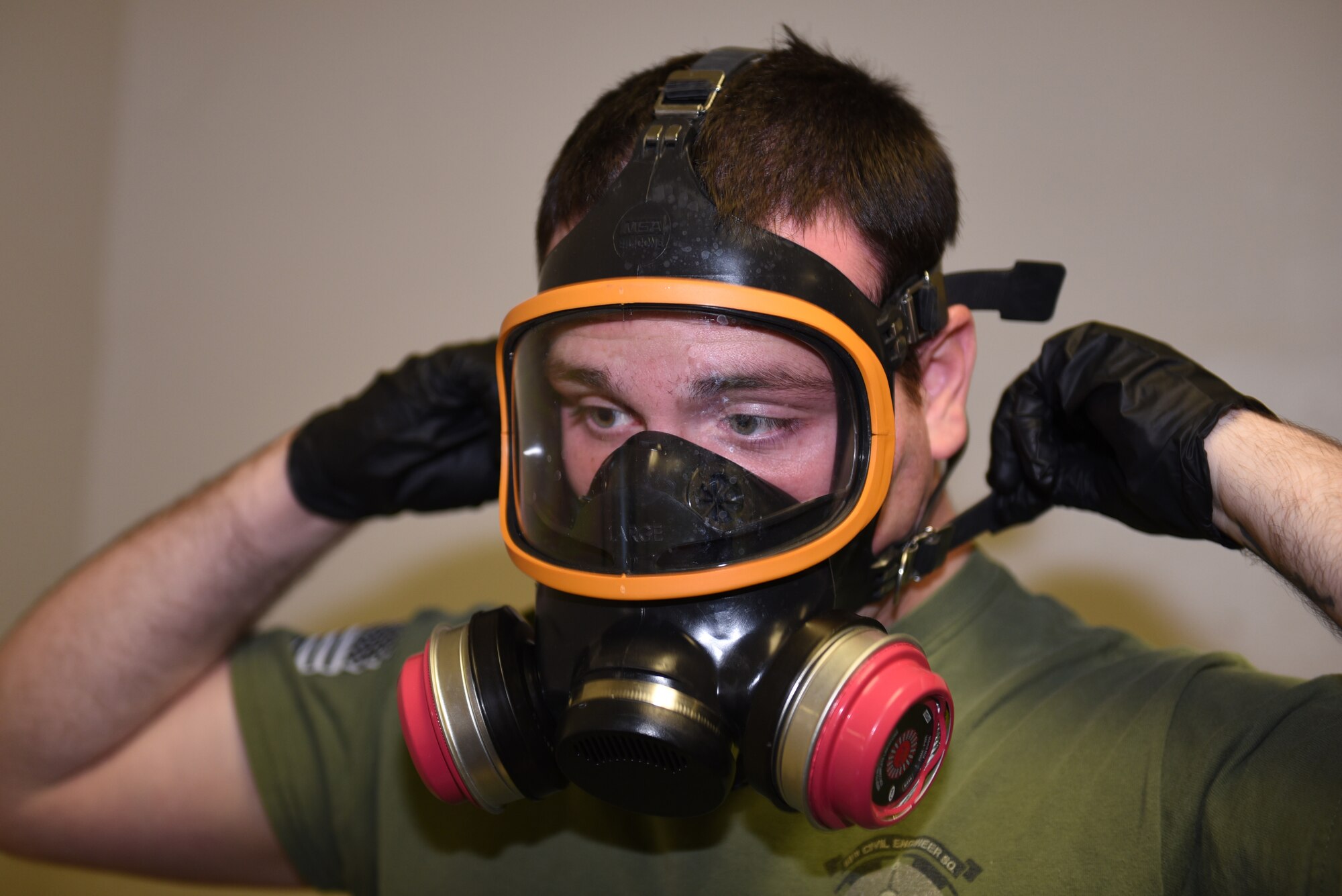U.S. Air Force Senior Airman David De Alva, 60th Civil Engineer Squadron pest management technician, puts on his gas mask to check if the filters are working properly Nov. 8, 2019, at Travis Air Force Base, California. De Alva uses the mask for fumigating jobs and spraying down Travis aircraft after they’ve returned from missions around the world. (U.S. Air Force photo by Airman 1st Class Cameron Otte)