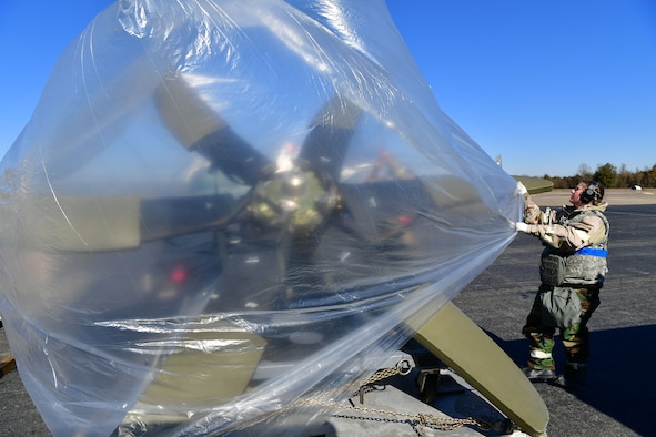 An Airman covers a C-130J propeller with a sheet of plastic