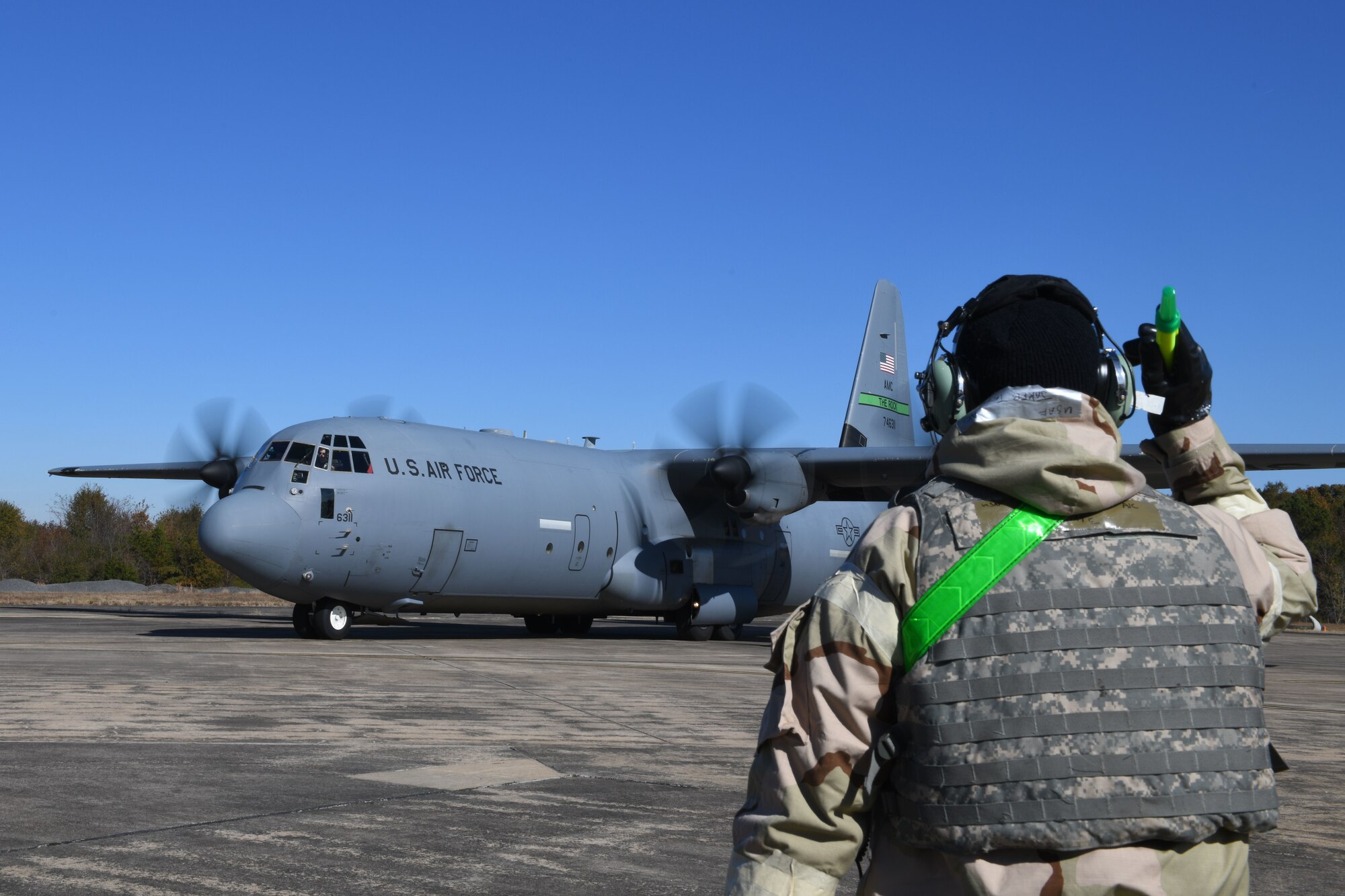 An Airman marshals a C-130J plane