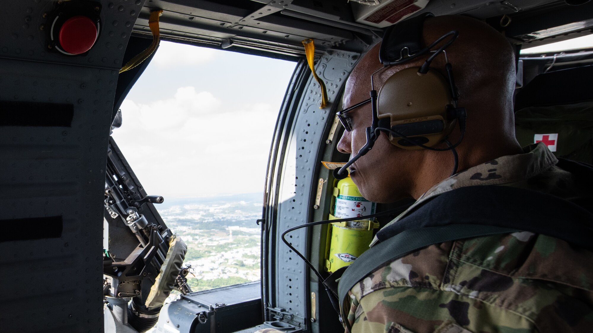 U.S. Air Force Gen. CQ Brown, Jr., Pacific Air Forces commander, looks out the window of an HH-60 Pave Hawk during an aerial tour of Kadena Air Base, Japan, Nov. 12, 2019. During the tour, Brown visited various base squadrons and agencies to learn about unit-specific issues, their operations, and answer questions. (U.S. Air Force photo by Staff Sgt. Benjamin Raughton)