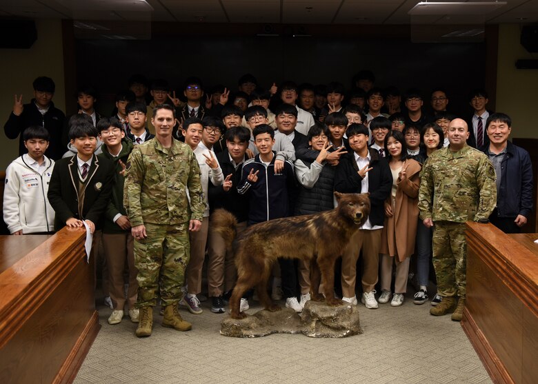 U.S. Air Force Col. Patrick Misnick, 8th Medical Group commander, and Chief Master Sgt. Steve Cenov, 8th Fighter Wing command chief, pose for a group picture with a group of students from Gunsan Dong High School during their visit at Kunsan Air Base, Republic of Korea, Nov. 8, 2019. The tour included meeting wing leadership, checking out an F-16 Fighting Falcon and observing an 8th Security Forces Squadron military working dog demonstration. (U.S. Air Force photo by Staff Sgt. Anthony Hetlage)