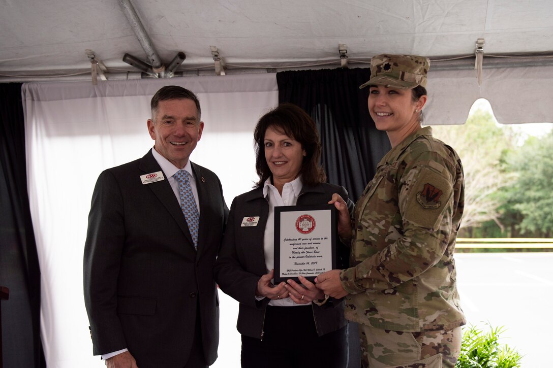 A photo of an Airman and people from the local community posing for a photo with an award during an event.