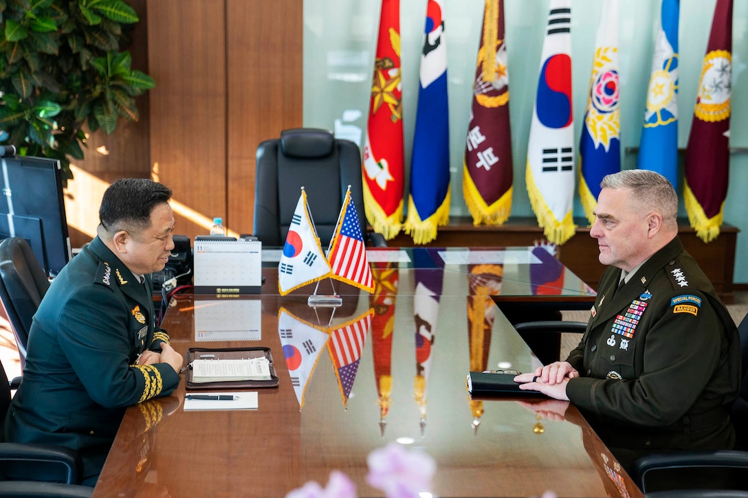 Two military leaders sit across from each other at a table.