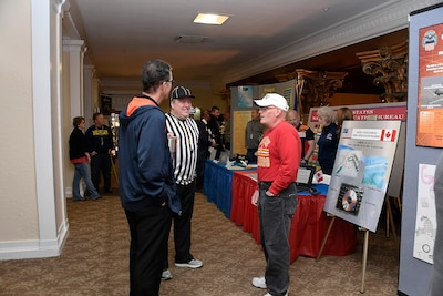 Three men talk in front of a display booth