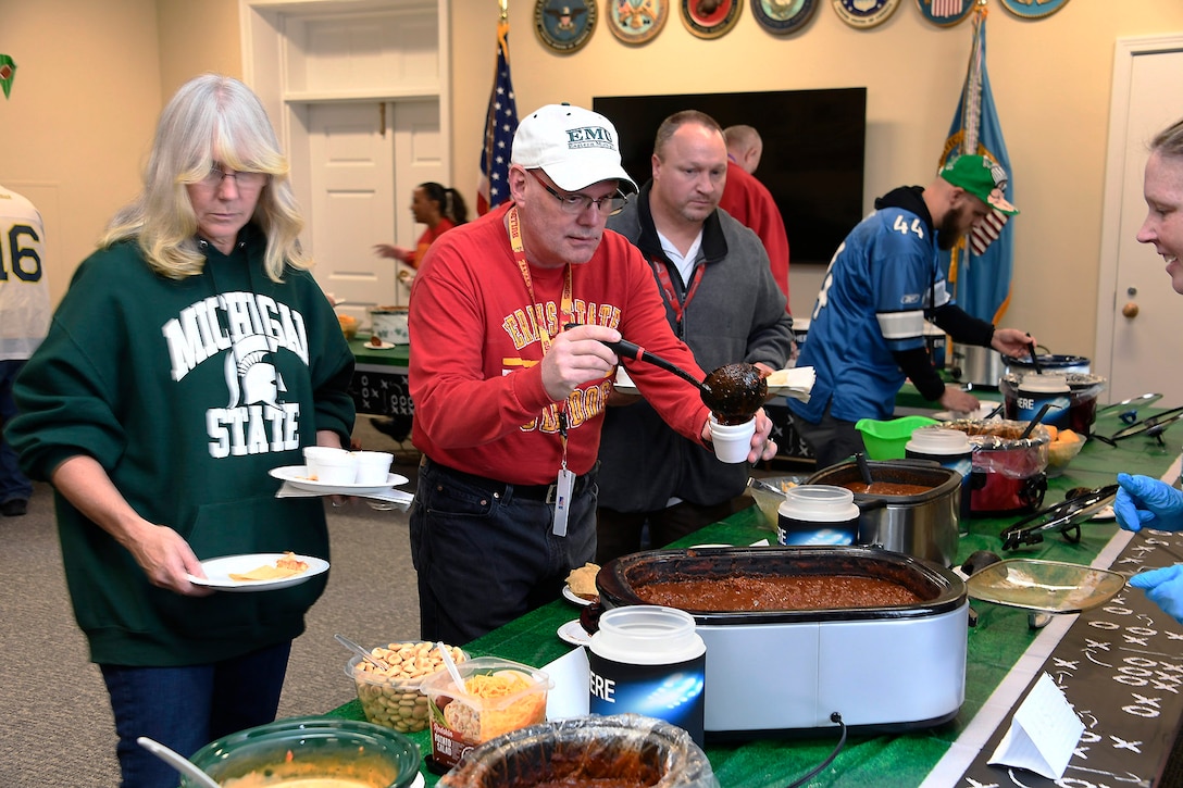 People fill their plates in a pot luck line.