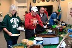 People fill their plates in a pot luck line.