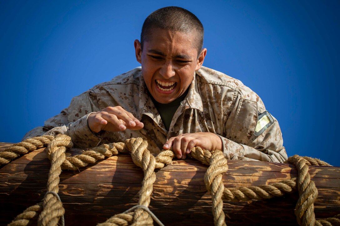 A Marine Corps recruit climbs over a cargo net.