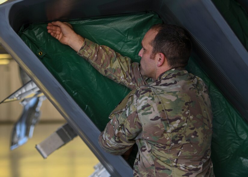 U.S. Air Force Tech. Sgt. Daniel Caban, 1st Aircraft Maintenance Squadron crew chief, applies a portion of the Portable Magnetic Aircraft Covers to an F-22 Raptor intake at Joint Base Langley-Eustis, Virginia, Oct. 23, 2019.