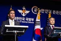 Two defense leaders stand  and answer questions.