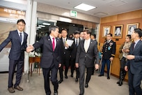Two men surrounded by a bunch of people walk through a doorway.