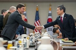 Two men shake hands over a large table.