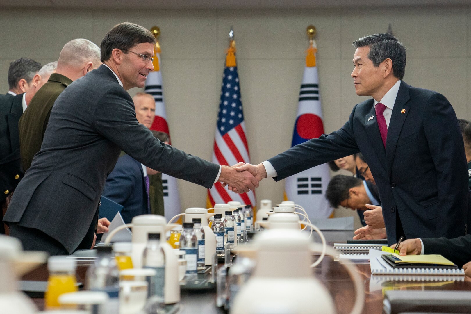 Two men shake hands over a large table.